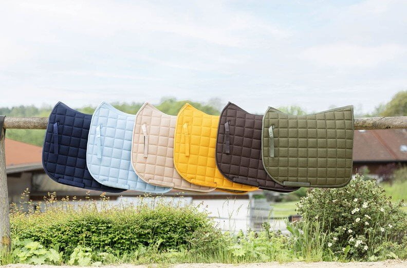 Covalliero zadeldekje paard Afbeelding van verschillende kleuren Covalliero zadeldekjes voor paarden hangend over een hek